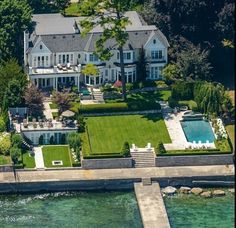 an aerial view of a large house with a dock in the foreground and swimming pool on the other side