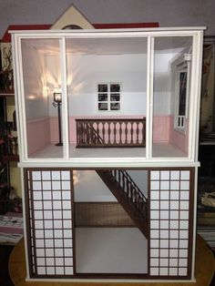 a doll house with stairs and windows in it