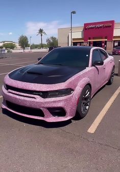 a pink and black car parked in a parking lot