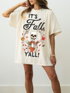 a woman wearing a white t - shirt that says it's fall y'all