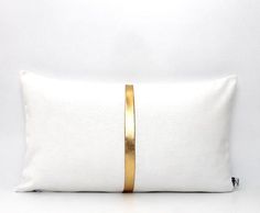 a white pillow with gold stripes on the front and back, against a white background