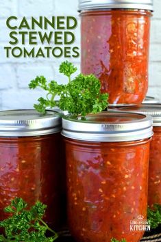 four jars filled with canned tomatoes and parsley