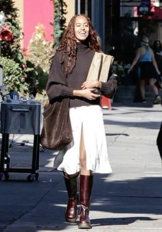 a woman is walking down the street wearing boots