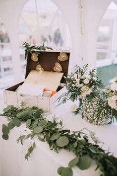 an open box sitting on top of a table filled with flowers and greenery next to other items