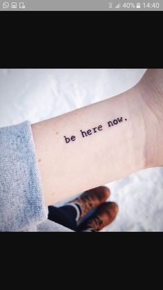 a person with a tattoo on their arm that says, be here now