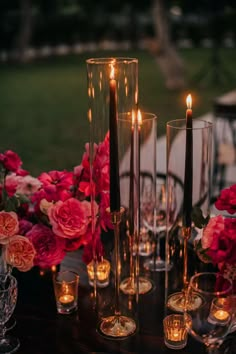 a table with candles and vases filled with flowers on top of it next to some wine glasses