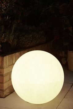 a large white ball light sitting on top of a cement wall next to a planter