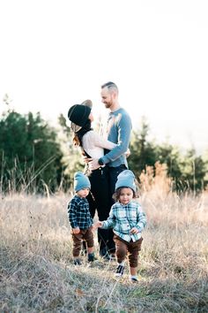 a man and two small children standing in the middle of a field with tall grass