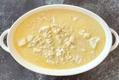 a white bowl filled with food sitting on top of a gray counter next to a knife