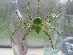 a green beaded spider sitting on top of a window sill next to a vase