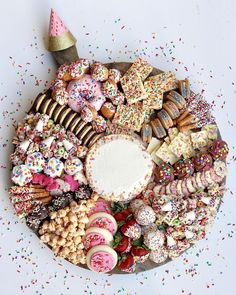 a platter filled with lots of different types of cookies and pastries on top of confetti