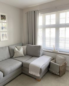 a living room with a gray couch and white curtains