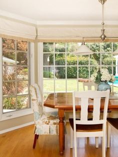 a dining room table and chairs in front of a large window with lots of windows