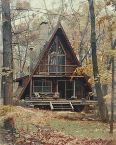 a - frame cabin nestled in the woods surrounded by trees and leaves on an autumn day