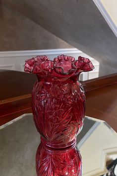 a red vase sitting on top of a glass table