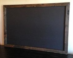 a black chalkboard sitting on top of a wooden table next to a white wall