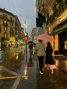 two people walking down the street with umbrellas