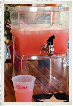 a drink dispenser sitting on top of a wooden table