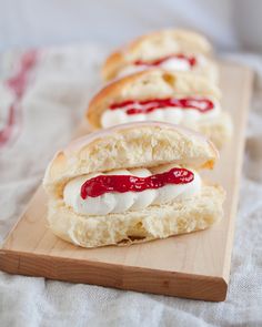 three hotdogs with cream cheese and ketchup on a cutting board