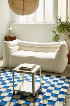 a living room with a large white couch and blue rug on the floor in front of a window