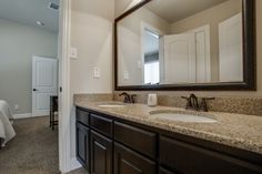 a bathroom with two sinks and a large mirror in it's center area, along with a bed