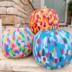 three painted pumpkins sitting on the front steps