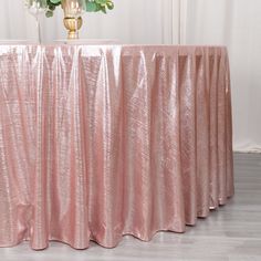 a table with a pink cloth on it and flowers in vases next to it