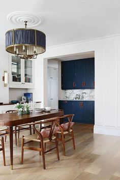 the dining room table is surrounded by blue cabinetry and chairs, along with a chandelier