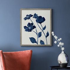 a blue and white painting hangs on the wall next to a chair with an orange cushion