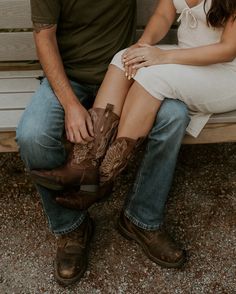 a man and woman sitting on a bench next to each other with cowboy boots around their ankles