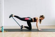 a woman is doing push ups on a yoga mat with a resistance band in her hand