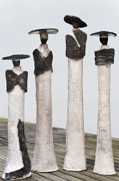 three sculptures made out of clay are standing on a wooden surface and one is holding an umbrella