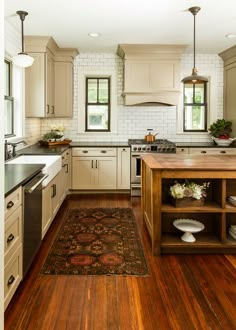 a large kitchen with wooden floors and white cabinets, along with an area rug on the floor