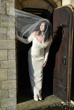 a woman in a white dress and veil is standing at the entrance to a church