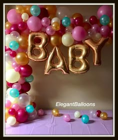 a baby balloon arch with the word baby spelled out in gold, pink, and blue balloons