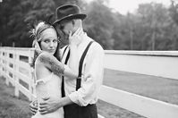 a man and woman standing next to each other in front of a white picket fence