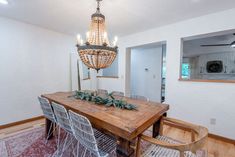 a dining room table with chairs and a chandelier hanging from it's ceiling