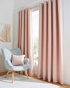 a living room with pink curtains and a blue chair in front of the window,