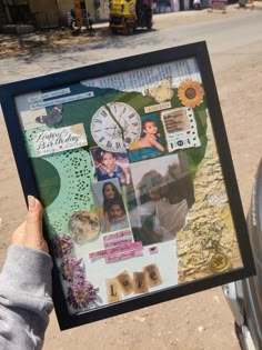 a person holding up a framed photo with pictures and words on it in front of a street