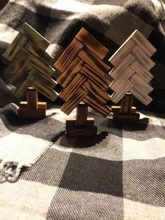 three wooden pieces are placed on top of a plaid blanket, one is shaped like an abstract tree