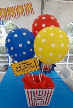 some balloons are sitting in a bucket on a blue table with red, white and blue decorations