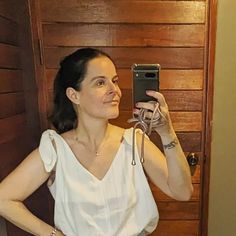 a woman taking a selfie in front of a wooden door with her cell phone