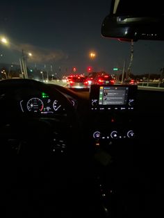 the dashboard of a car is lit up at night with traffic lights in the background