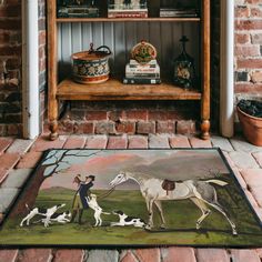 a rug with a painting of two horses and three dogs on it in front of a bookshelf