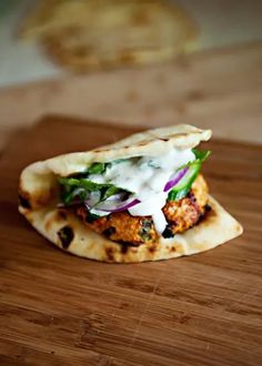 a chicken pita sandwich on a wooden cutting board