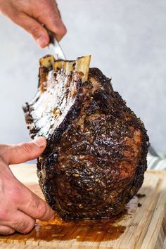 a person cutting up a piece of meat with a knife on a wooden cutting board