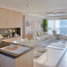 a living room filled with furniture next to a kitchen and dining room table in front of a large window