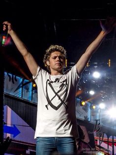 a man with his arms up in the air at a music concert, holding two microphones above his head