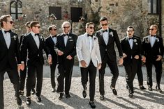 a group of men in tuxedos walking down the street with one man wearing sunglasses