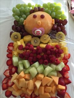 a platter filled with lots of fruit and a teddy bear on top of it